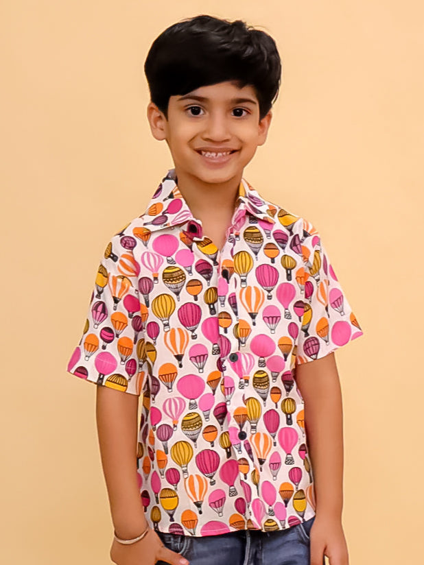 Child wearing a colorful patterned shirt and jeans on a beige background