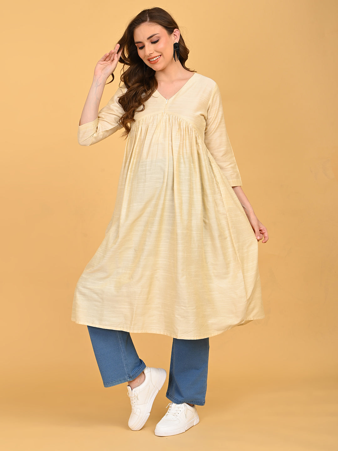 Pregnant model wearing cream silk maternity and nursing kurta with V-neckline, paired with blue straight-fit pants and white sneakers.