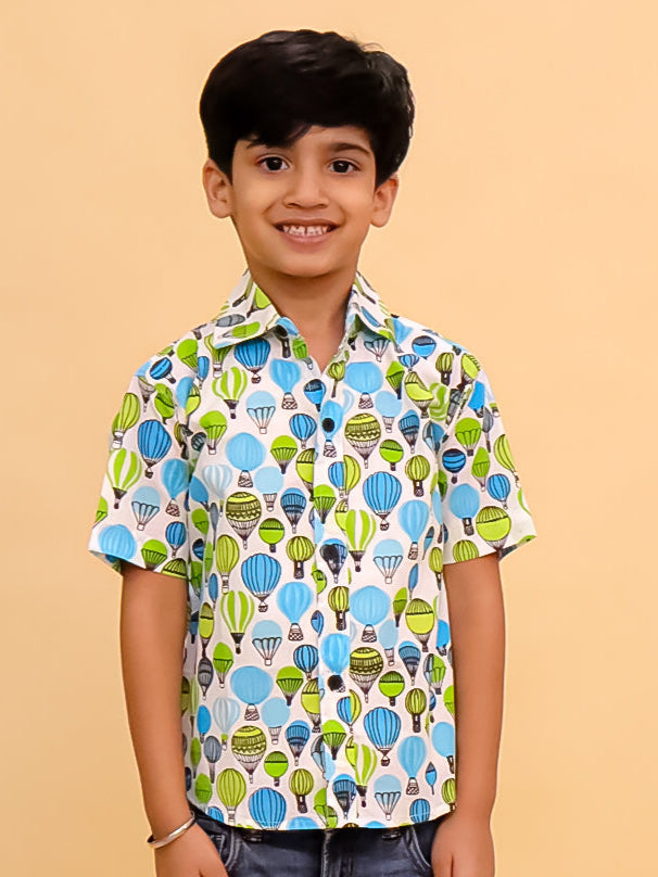 Child wearing a colorful shirt with hot air balloon pattern on a beige background