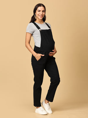 relaxed pose of pregnant woman in The Mom Store black Denim Maternity Dungaree with Side Buttons 