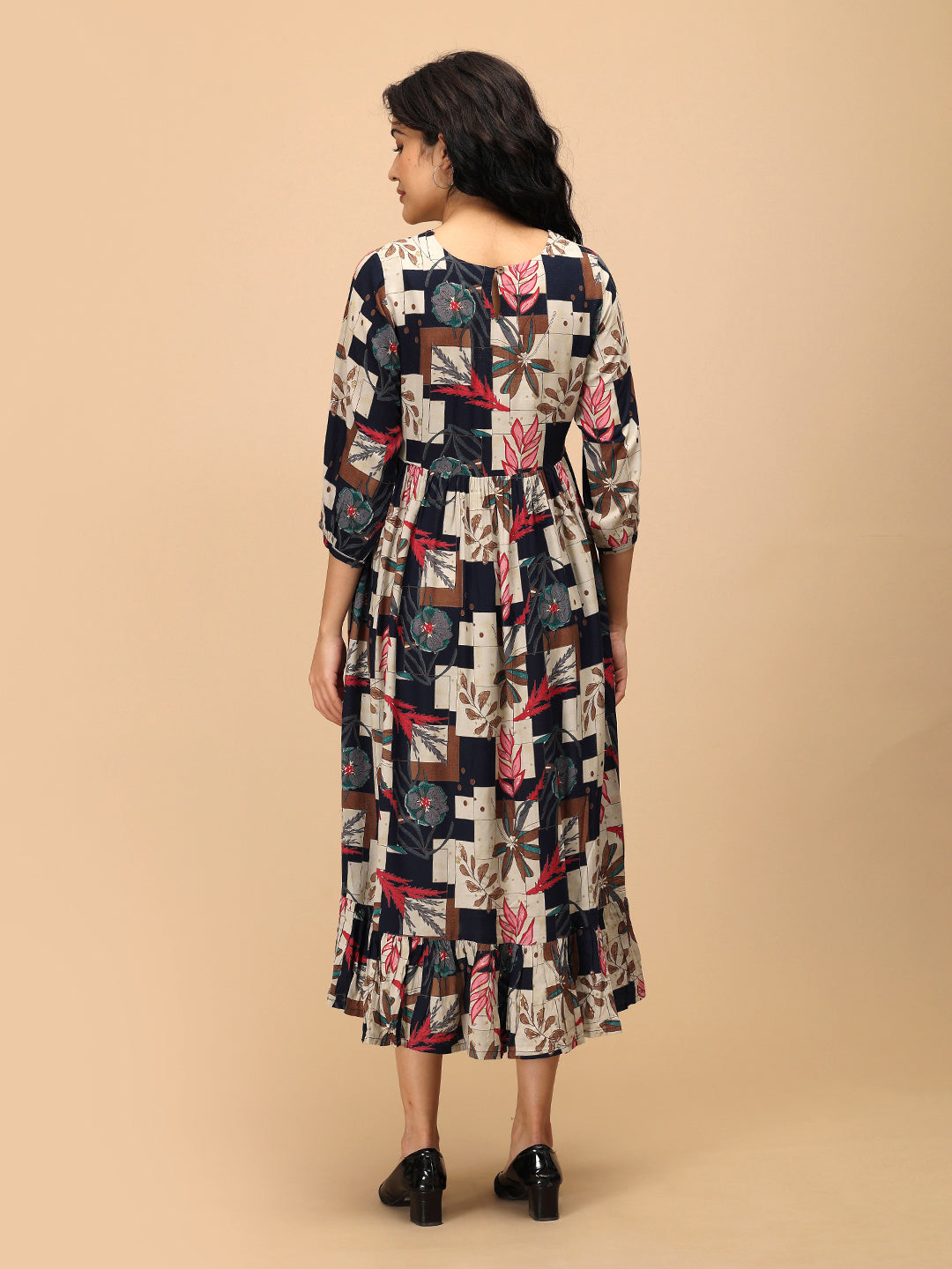 Back view of The Mom Store Muted Muse maternity dress with patch-print floral pattern and ruffle hem.