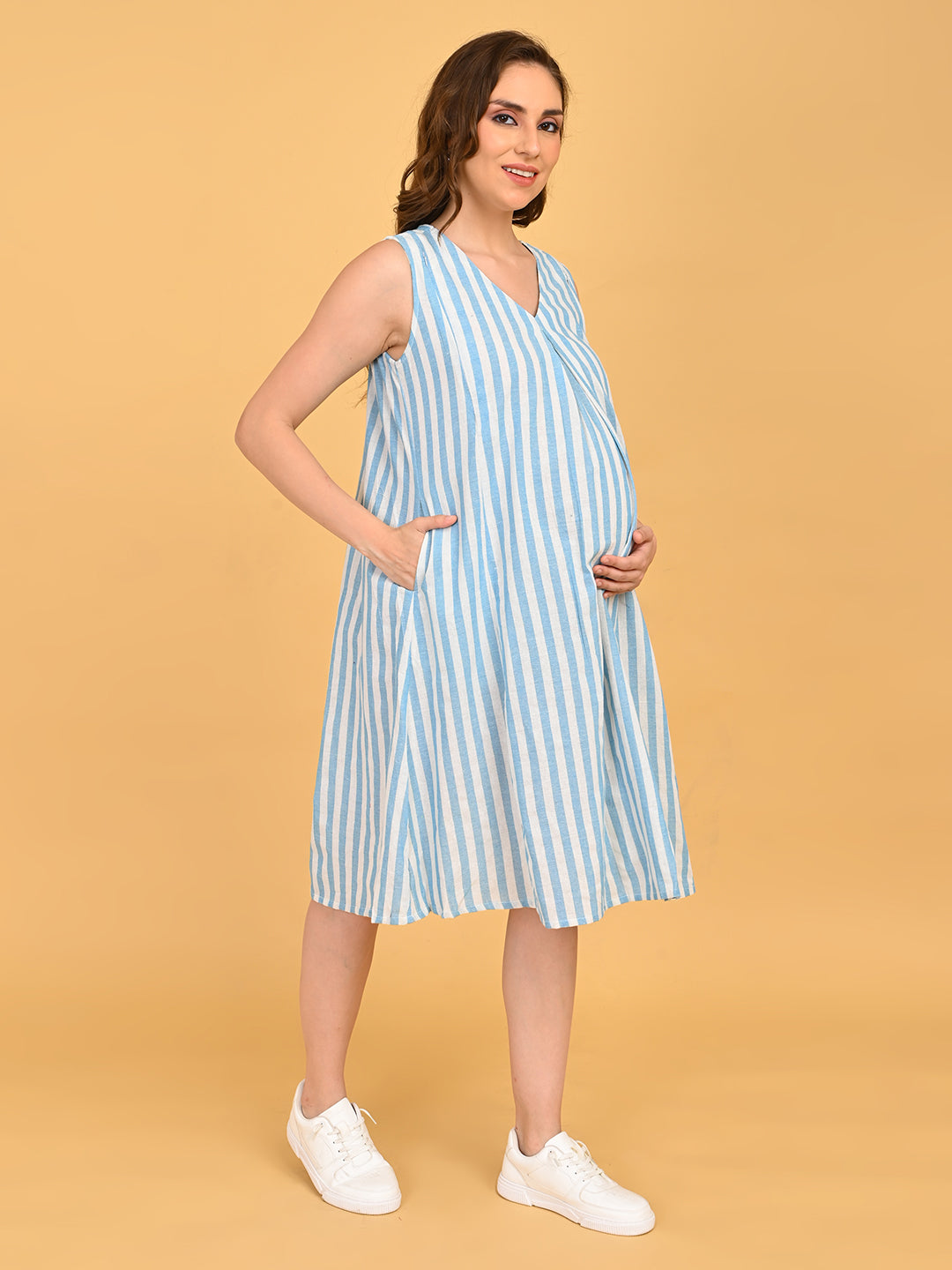 Pregnant model wearing blue and white striped sleeveless maternity dress with V-neckline and knee-length silhouette.