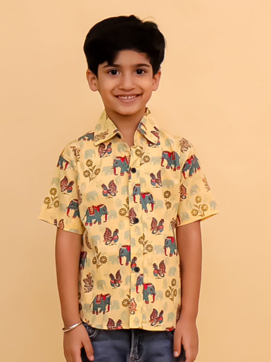 Child wearing a yellow patterned shirt and blue jeans on a beige background