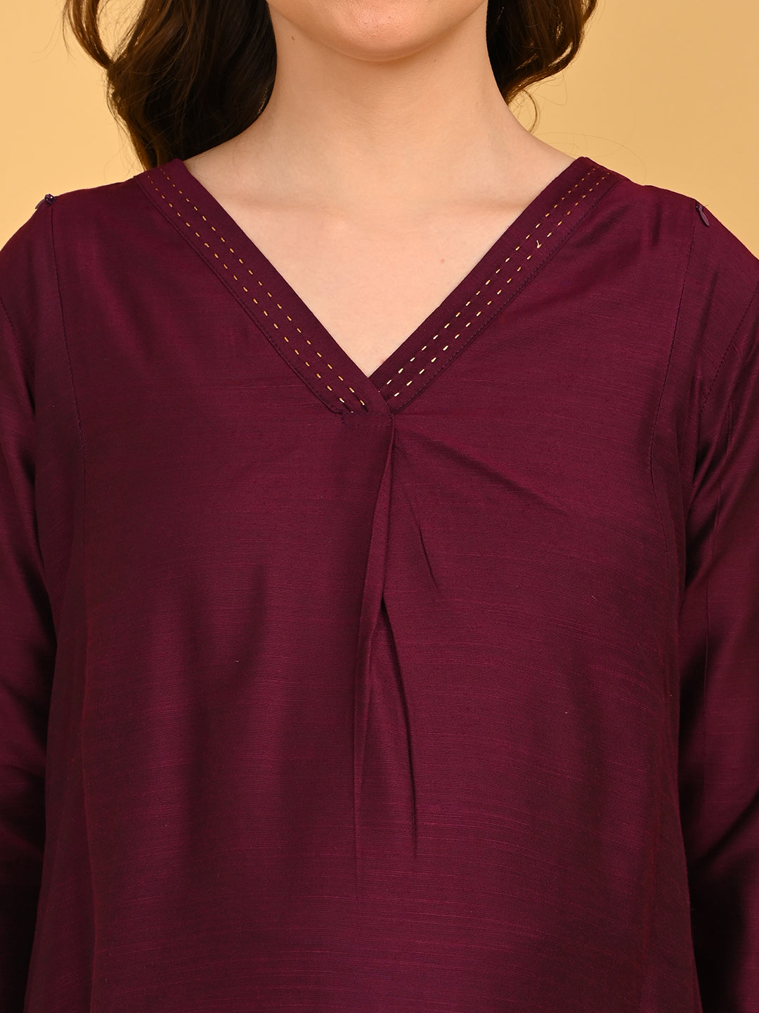 Close-up of wine silk maternity kurta featuring V-neckline with delicate embroidered stitch detailing.