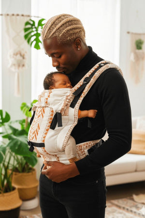 Dad bonding with newborn in Almitra Tattva linen baby carrier, ergonomic front carry position, soft breathable fabric, adjustable support straps, inclusive babywearing for fathers and caregivers