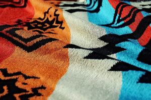 Extreme close-up of the woven texture of the Auronee baby wrap, showing the high-quality thread work and vibrant dye in turquoise, rust, and black. The fabric's breathable weave is perfect for all-season babywearing.