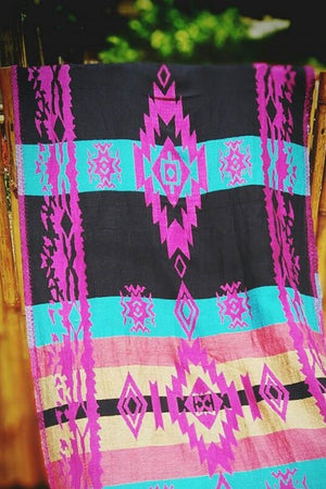 Close-up shot of the Almitra Tattva Pema woven wrap fabric, showcasing the intricate Kullu inspired geometric weave in vibrant pink, cyan blue, and deep black.