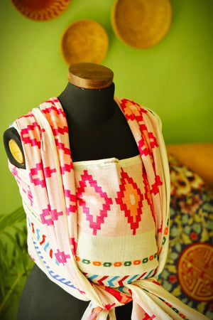 Front view of Almitra Tattva Shubra woven baby wrap with bold pink tribal inspired geometric weave and colorful boho border detailing.