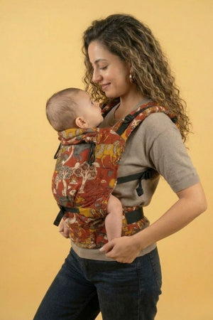 Smiling parent carrying baby in the Almitra Tattva Jataka Tales soft structured carrier featuring bold Indian Kalamkari artwork and inclusive ergonomic design. Adjustable infant and toddler carrier with breathable fabric, secure support, and stylish ethnic-inspired print for modern parents.