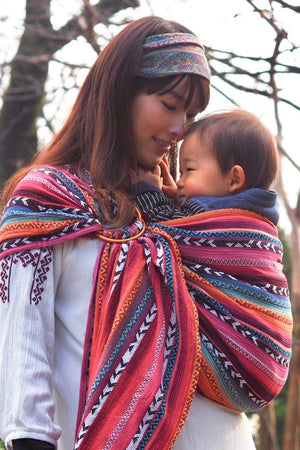 Parent bonding with baby in Almitra Tattva Larona Bohemian Ring Sling featuring vibrant handcrafted woven patterns, soft adjustable baby carrier fabric, ergonomic support, and comfortable everyday babywearing.