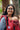 Young mother outdoors using Almitra Tattva red sustainable baby carrier with ergonomic shoulder support, breathable fabric, and comfortable front babywearing design.