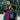 A bearded father wearing a toddler in an Almitra Tattva Pema Wrap Converted Ring Sling from the Kullu Collection. The sling features vibrant pink, turquoise, and black geometric handwoven patterns with a pink aluminum ring. The setting is a snowy winter landscape, emphasizing the bold, inclusive style of the brand.