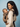 Side profile of a mother wearing a cream knit sweater and looking down lovingly at her baby secured in the taupe Tushi baby carrier.