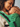 Intimate close-up of an infant asleep against their mother's chest inside the green handloom Mangalgiri cotton carrier panel.