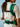 Rear view of a woman showing the horizontal chest clip, padded green shoulder straps, and wide lumbar waist buckle of the carrier.