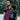 A bearded father wearing a toddler in an Almitra Tattva Pema Wrap Converted Ring Sling from the Kullu Collection. The sling features vibrant pink, turquoise, and black geometric handwoven patterns with a pink aluminum ring. The setting is a snowy winter landscape, emphasizing the bold, inclusive style of the brand.