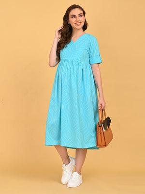 Aquamarine Affair Maternity and Nursing Dress featuring an empire waist, V-neckline, and all-over print, paired with white sneakers and a structured tan handbag.