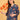 Pregnant model posing in blue floral maternity and nursing dress while holding decorative orange leaves.