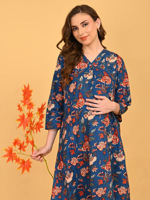 Pregnant model posing in blue floral maternity and nursing dress while holding decorative orange leaves.