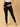 A pregnant woman wearing black maternity leggings with a wide, belly support waistband, paired with a short grey top