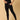 A pregnant woman wearing black maternity leggings with a wide, belly support waistband, paired with a short grey top.