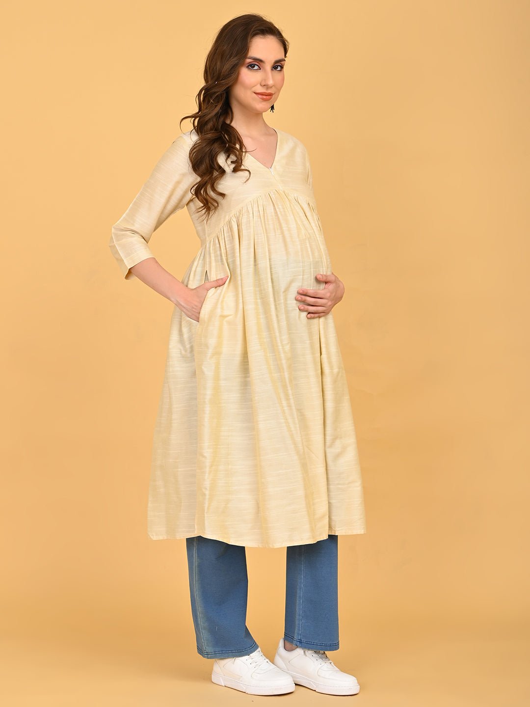 Cream maternity silk kurta with flared gathered design styled with blue pants.