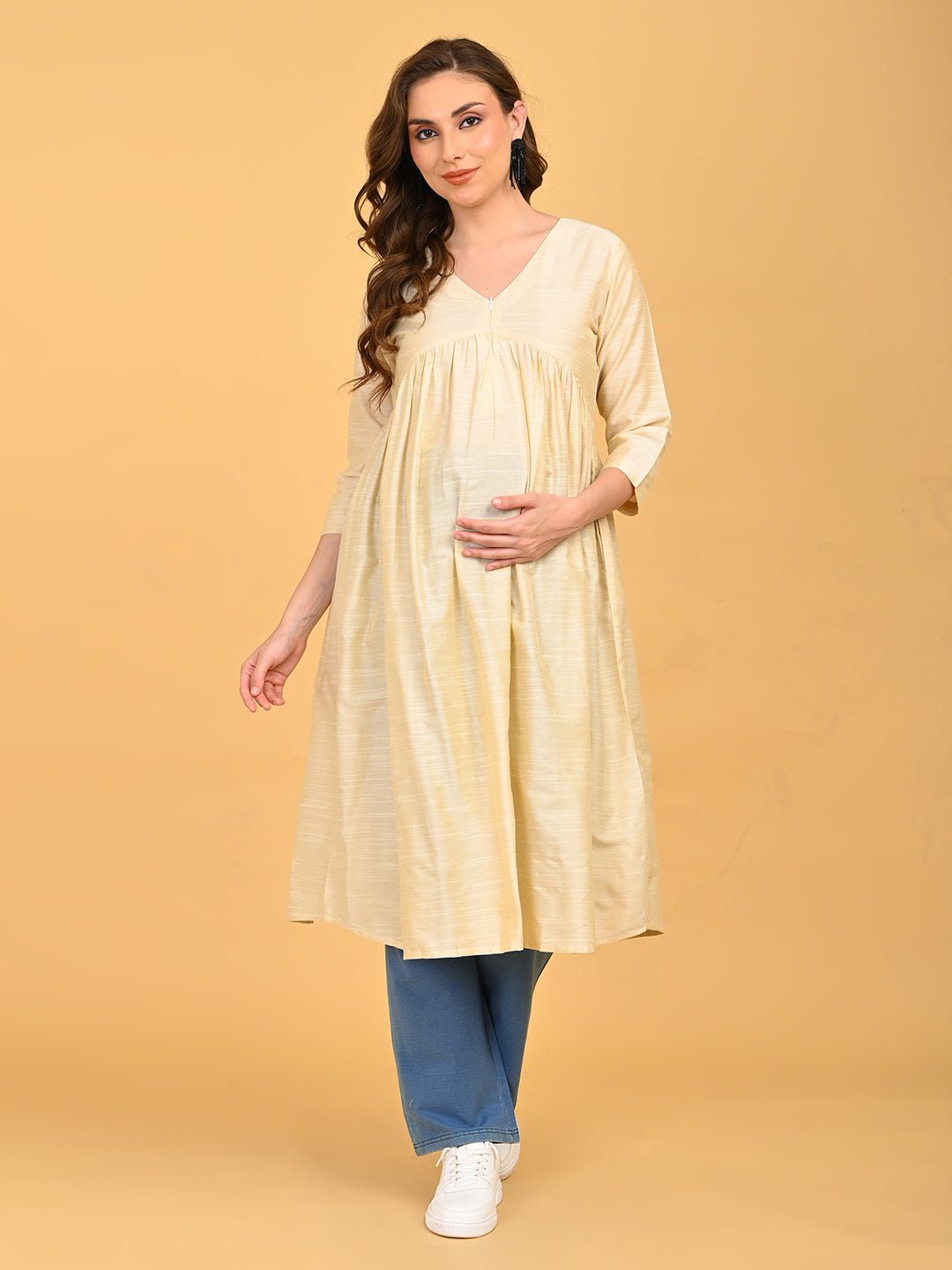 Pregnant model walking in cream maternity kurta with flowy silhouette and three-quarter sleeves.