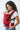 Side profile of a mother and baby making eye contact, showcasing the ergonomic seat and padded shoulder straps of the red Aruna cotton carrier.