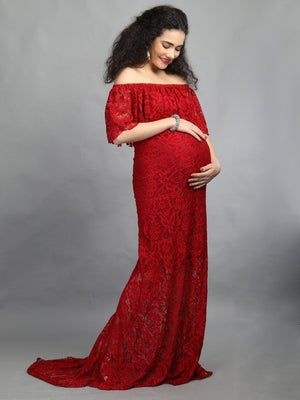 Side View of a pregnant lady wearing wine coloured, off-shoulder maternity maxi dress from The Mom Store, touching her bump.