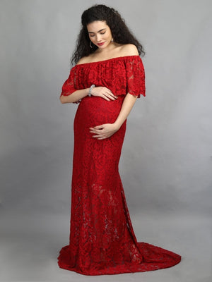 A visibly pregnant model wearing wine coloured, off-shoulder maternity maxi dress from The Mom Store, touching her bump.