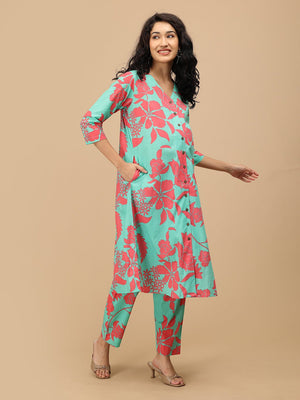 Model wearing a mint green floral maternity and nursing kurta with matching pants, featuring coral floral prints and a V-neck button-down front.