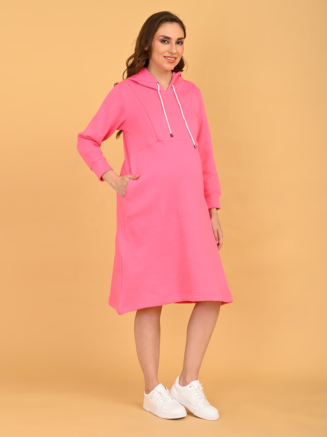Side view of fuchsia maternity hoodie dress highlighting bump-friendly fit and side pocket detail.