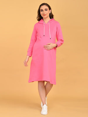 Pregnant model walking in fuchsia maternity and nursing hoodie dress styled with white sneakers.