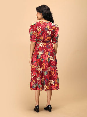 Back view of a woman wearing a garnet red floral maternity and nursing wrap dress with short puff sleeves and a midi-length flared hem.