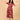 Woman posing with raised arms in a garnet red floral maternity and nursing wrap dress featuring a vibrant leaf print.
