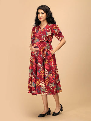 Side view of a garnet red floral maternity and nursing wrap dress showing the adjustable waist tie and flowing skirt.