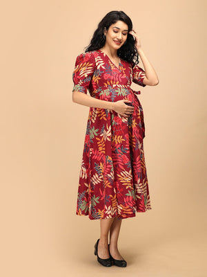 Woman gently holding her baby bump while wearing a garnet red floral maternity and nursing wrap dress.
