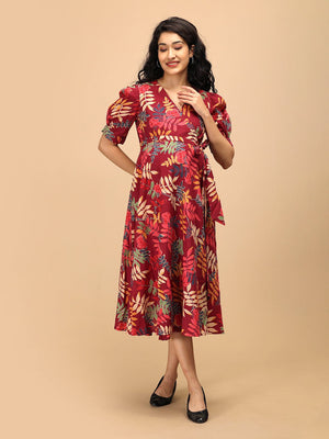 Woman gently holding her baby bump while wearing a garnet red floral maternity and nursing wrap dress.