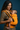 Close-up view of the mother holding the padded black shoulder strap adjustment on the orange and yellow Ikkat baby carrier.