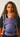 Front portrait of a woman wearing the Almitra Tattva Nilopala carrier, displaying the full front body panel, folded neck support, and wide patterned waistband.