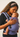 Close-up of a mother gently kissing the forehead of her sleeping baby secured in the blue patterned Nilopala baby carrier.