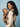 Side profile of a mother wearing a cream knit sweater and looking down lovingly at her baby secured in the taupe Tushi baby carrier.