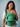 Front view of a smiling mother standing and wearing the green diamond-patterned Almitra Tattva Yaman Yoga carrier with her baby positioned inside.