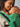 Intimate close-up of an infant asleep against their mother's chest inside the green handloom Mangalgiri cotton carrier panel.