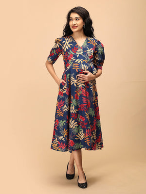 Woman wearing a navy blue floral maternity and nursing wrap dress with short puff sleeves and a tie-up waist.
