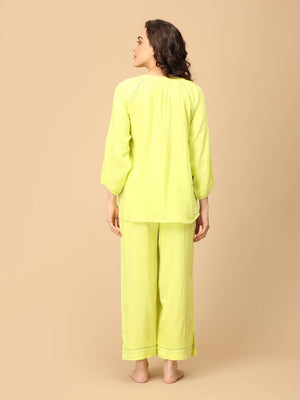 Playful pose by model wearing Lime - o - Clock Maternity and Nursing Nightwear Set from the mom store touching her belly and turned backwards