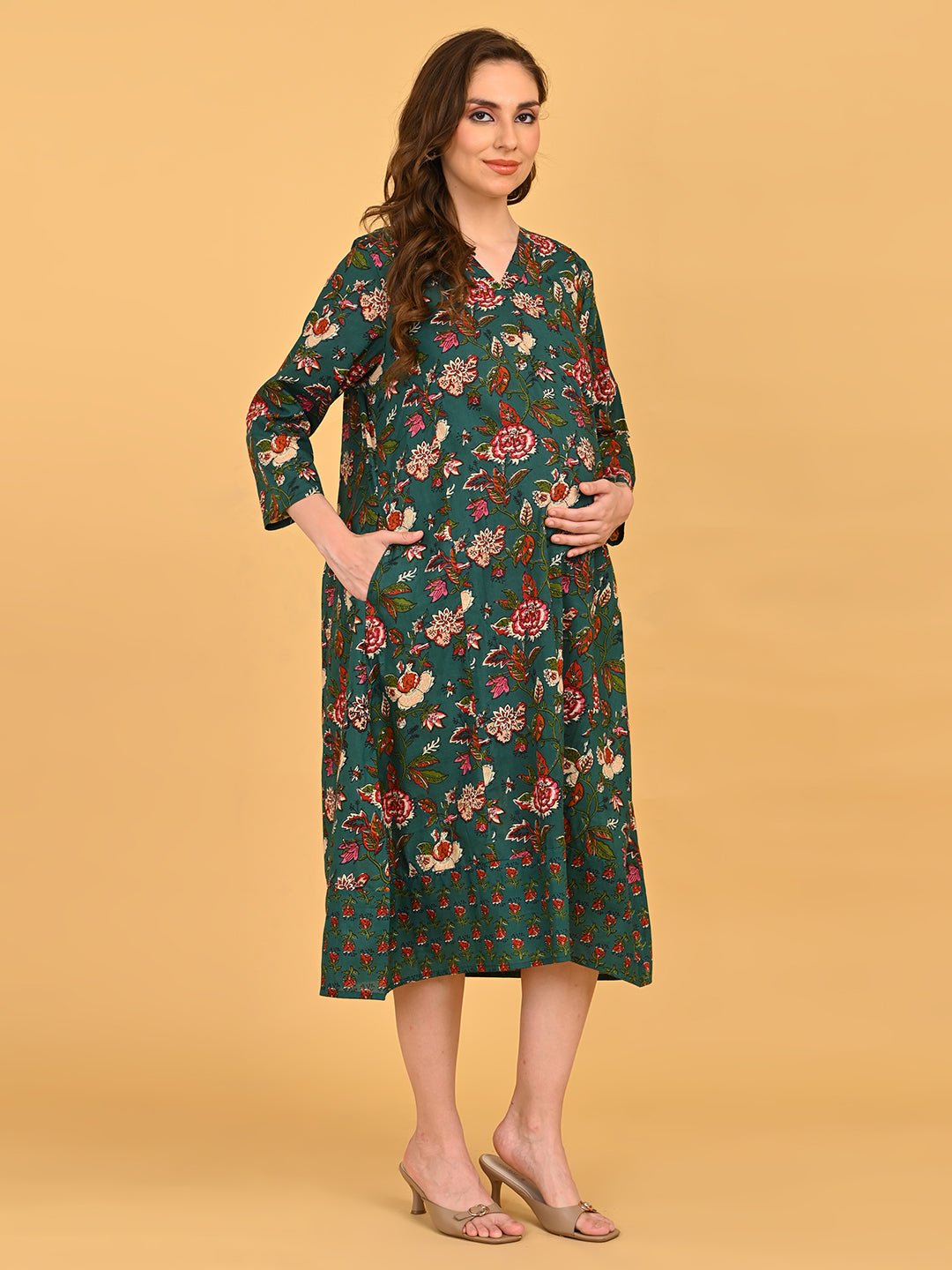 Smiling pregnant model wearing green floral maternity dress with relaxed A-line silhouette.