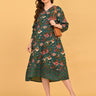 Model styling green floral maternity midi dress with sunglasses, tan shoulder bag, and beige heels.