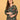Pregnant model posing in green floral maternity dress with hand on bump and sunglasses in hand.