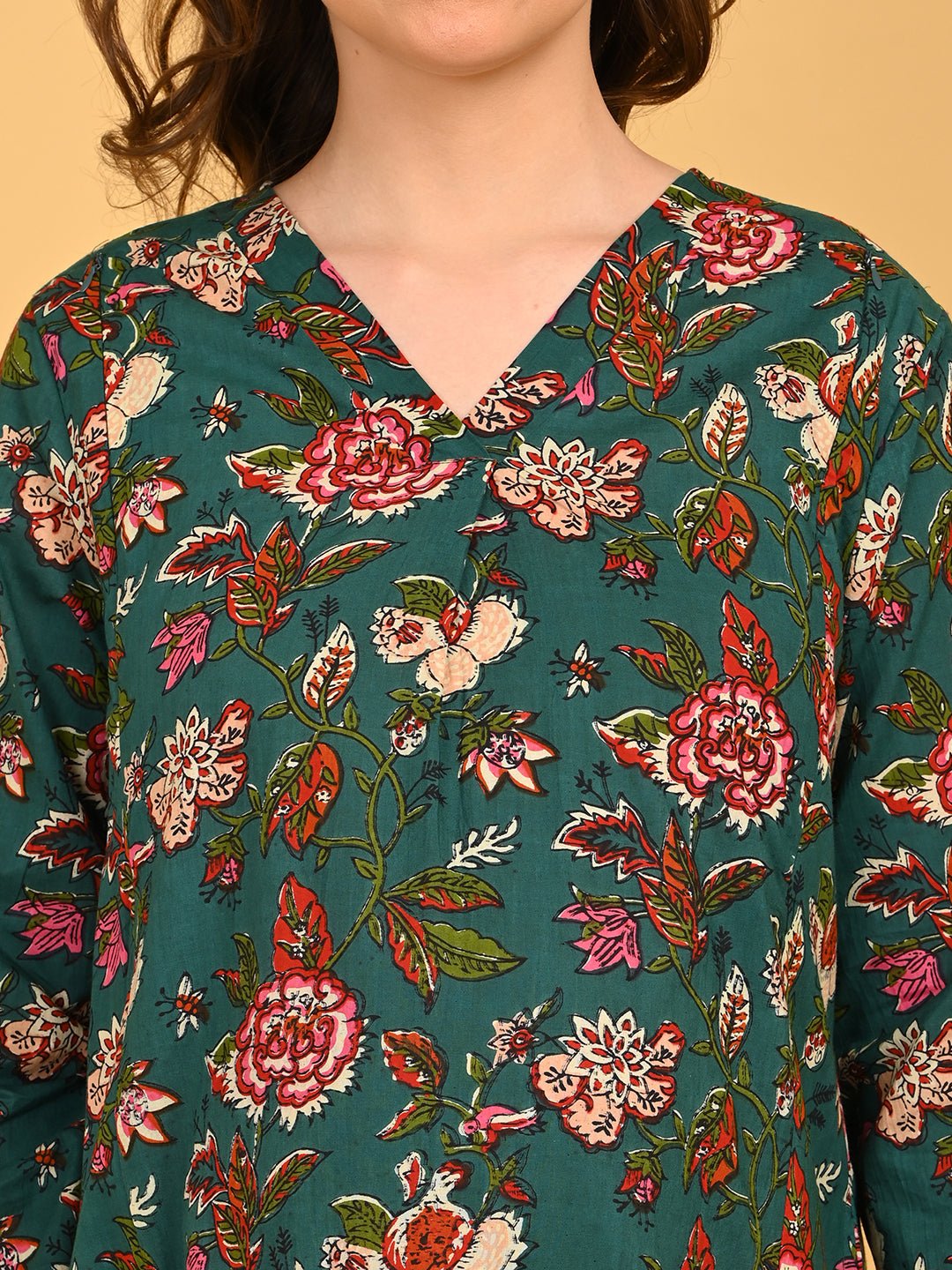 Close-up of green floral maternity dress featuring V-neckline and vibrant pink and cream floral print.